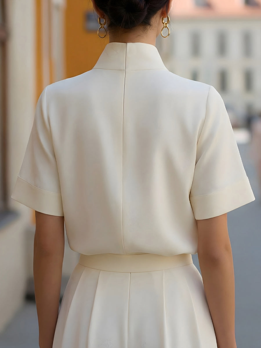 White structured blouse with stand collar and short sleeves, back view with center seam