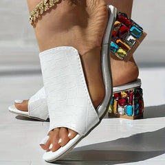 White croc-texture slide heels with jeweled block heel and open toe, ankle bracelet visible