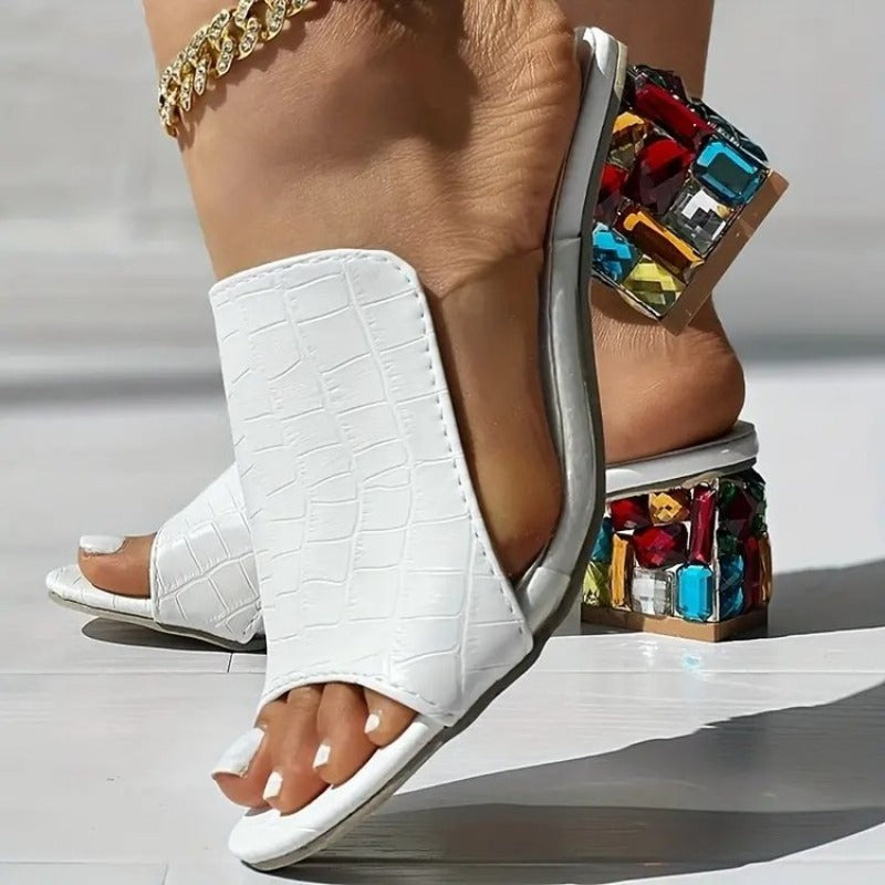White croc-texture slide heels with jeweled block heel and open toe, ankle bracelet visible