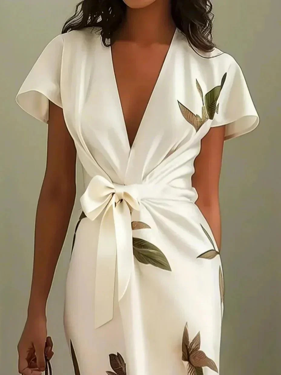 White wrap dress close-up: deep V neckline and bow-tie waist with bird print