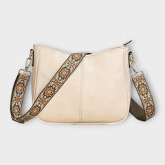 Cream crossbody bag with patterned strap, chain links, and zip-top closure