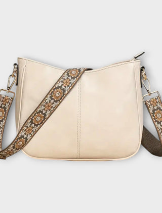 Cream crossbody bag with patterned strap, chain links, and zip-top closure