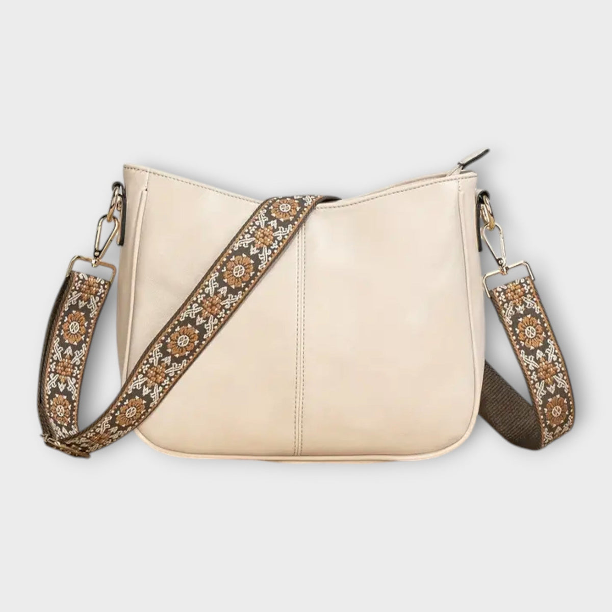 Cream crossbody bag with patterned strap, chain links, and zip-top closure
