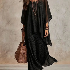 Black bohemian maxi dress with dark leopard print skirt, sheer cape sleeves, tiered hem