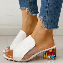 White croc-texture open-toe slide heels with colorful jeweled block heel, worn with denim