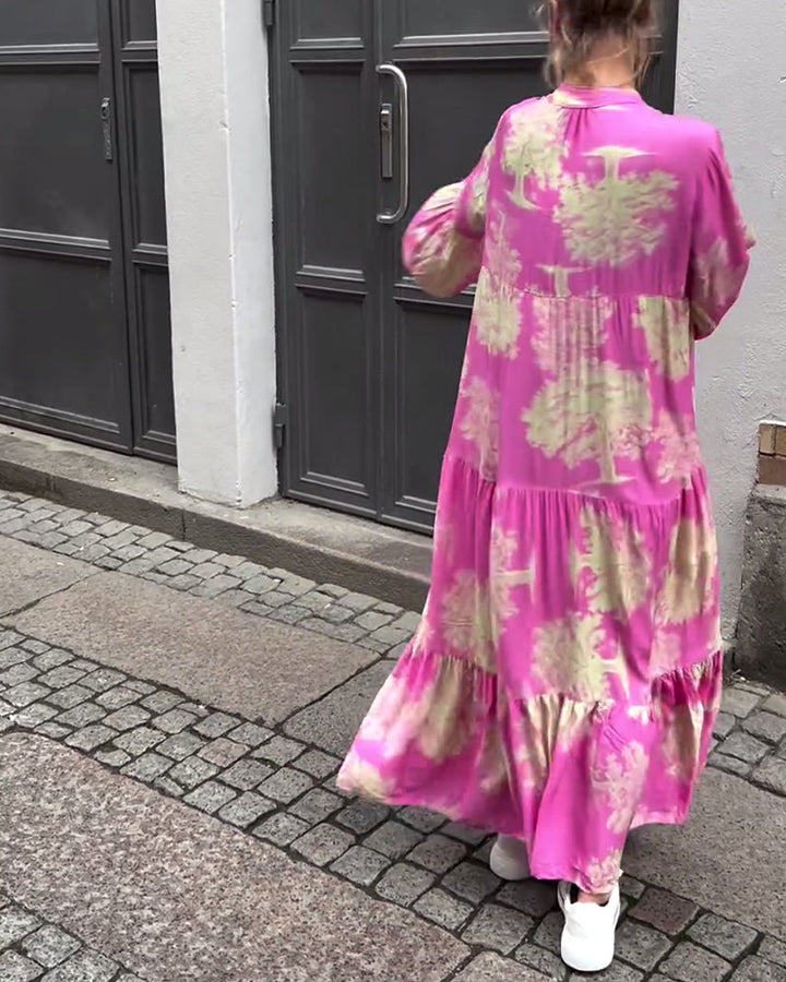 Back view of pink maxi dress with cream abstract print and tiered ruffle hem.