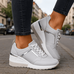 White lace-up sneakers with perforated toe and chunky white-and-gray sole.