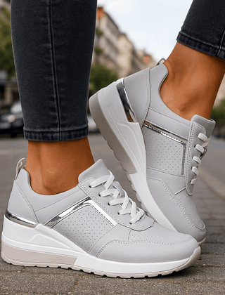 White lace-up sneakers with perforated toe and chunky white-and-gray sole.