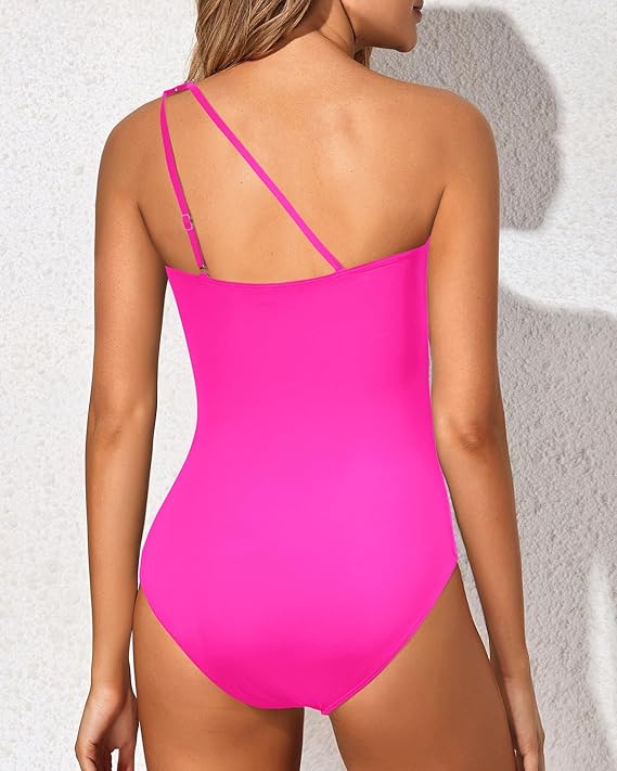 One-shoulder fuchsia swimsuit with open back and slim adjustable straps.