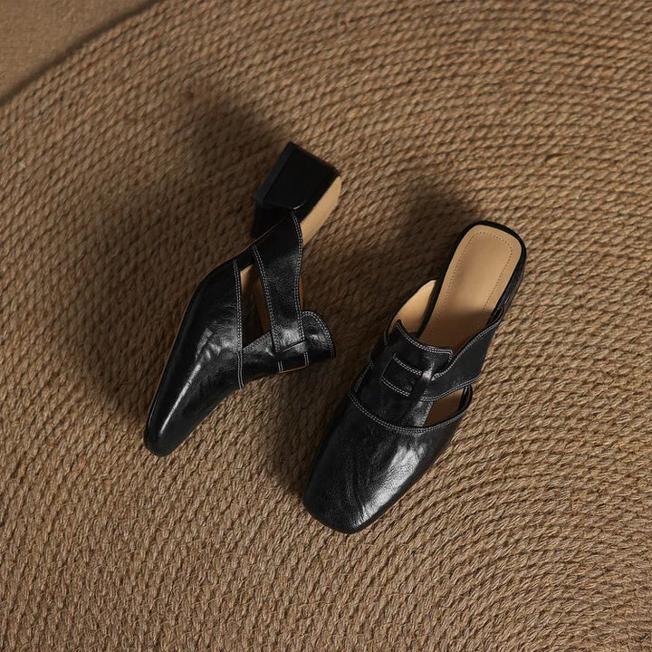 Black leather mule pair, one angled showing buckle strap and low block heel