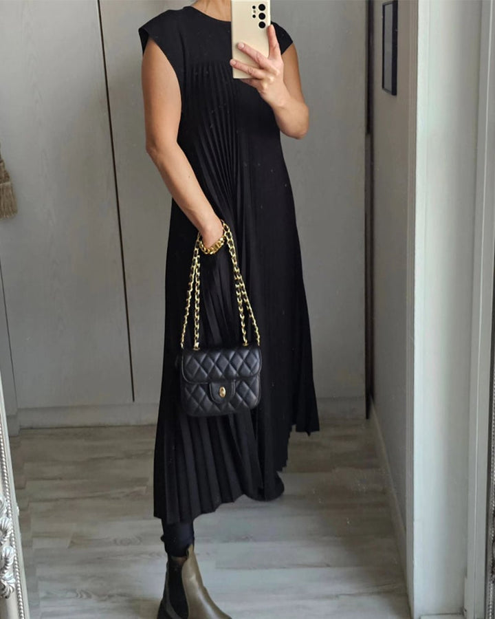 Black pleated maxi dress with short sleeves and long draped silhouette, with crossbody bag