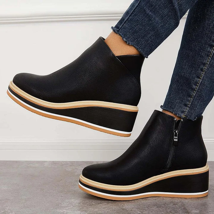 Black leather-look ankle boots with side zipper and tan-trimmed soles