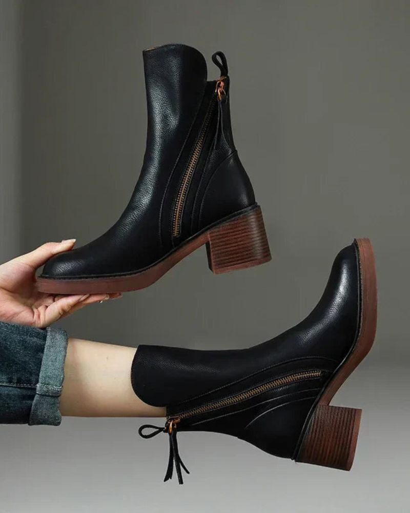 Black leather ankle boots with side zipper, tassel pull, and stacked block heel.