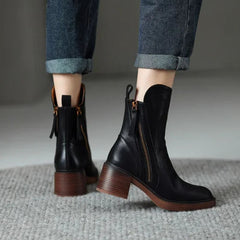 Black leather ankle boots with side zipper and tassel pull, block heel on textured rug.