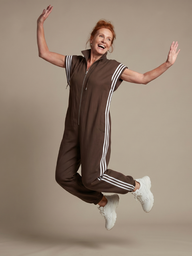 Brown zip stripe jumpsuit with short sleeves, white side stripes, and drawstring hood