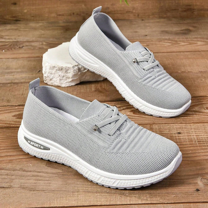 Gray lace-up knit sneakers with white soles, angled view on light blocks