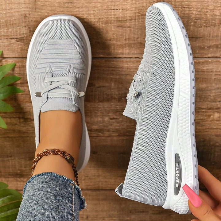 Gray lace-up sneakers side view with white outsole and branding on midsole