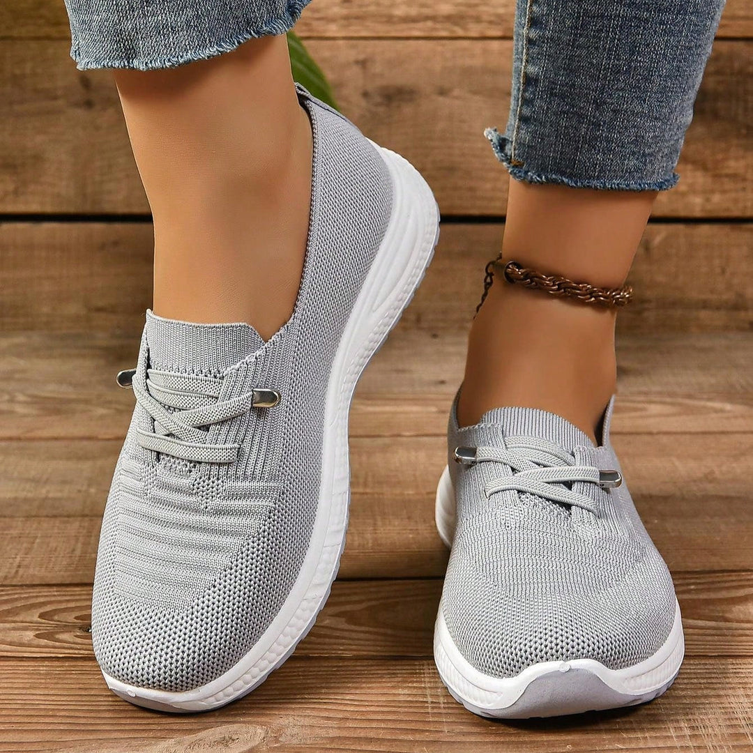 Pair of gray lace-up sneakers with white soles, shown on feet