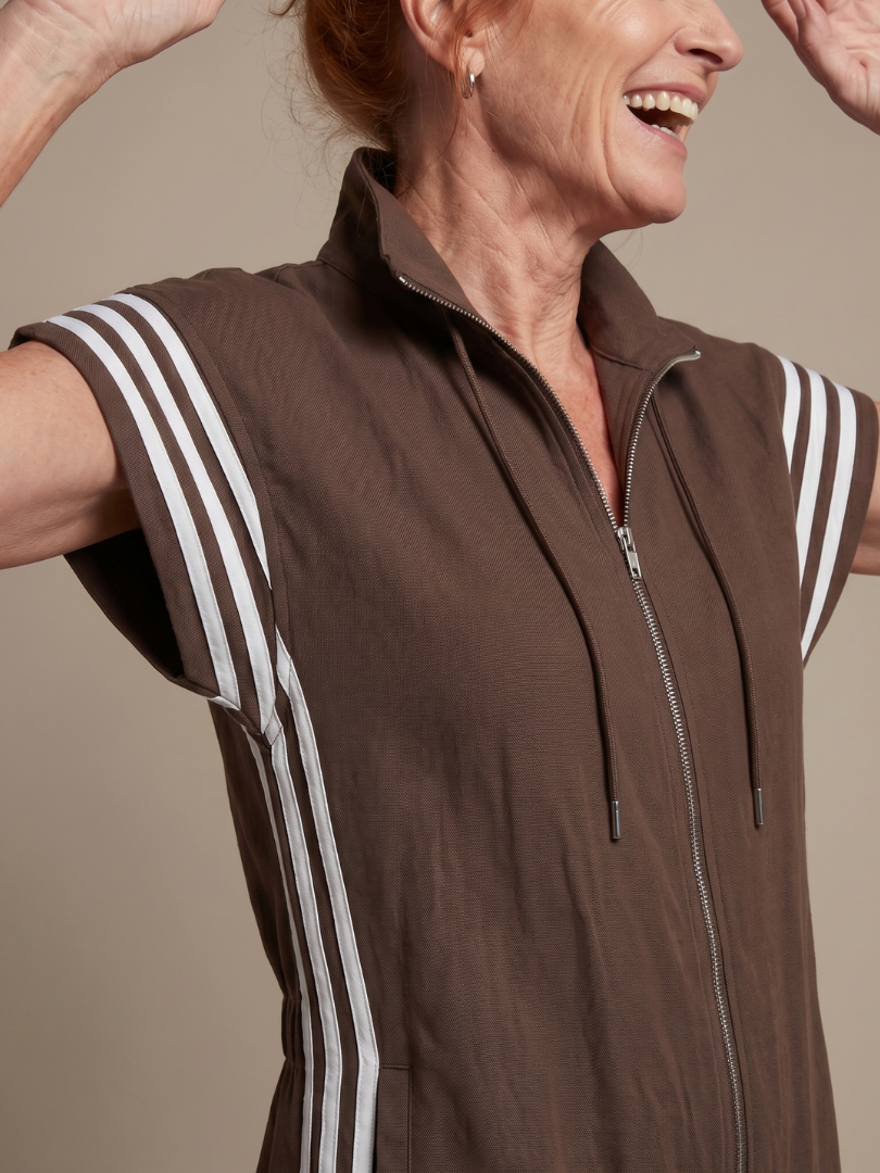 Brown zip jumpsuit close-up with stand collar, drawstring ties, and white striped sleeves
