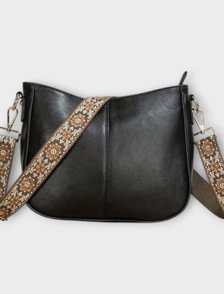 Black crossbody bag with patterned strap, chain links, and zip-top closure