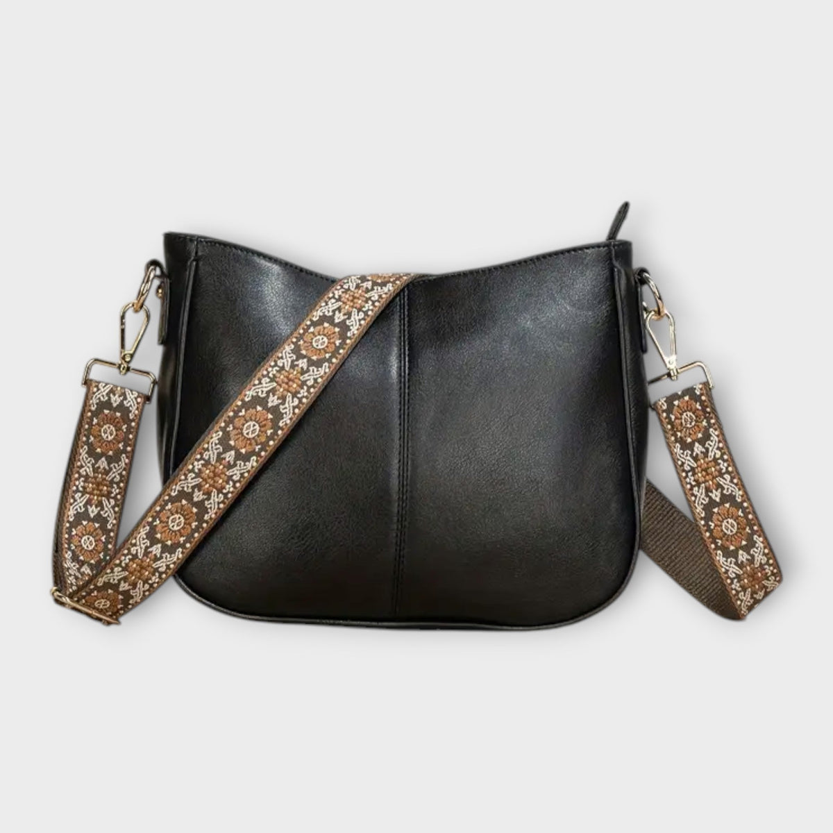 Black crossbody bag with patterned strap, chain links, and zip-top closure