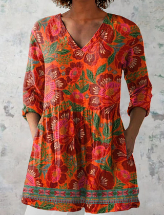 Long-sleeve V-neck blouse in red-orange with colorful floral print and gathered waist