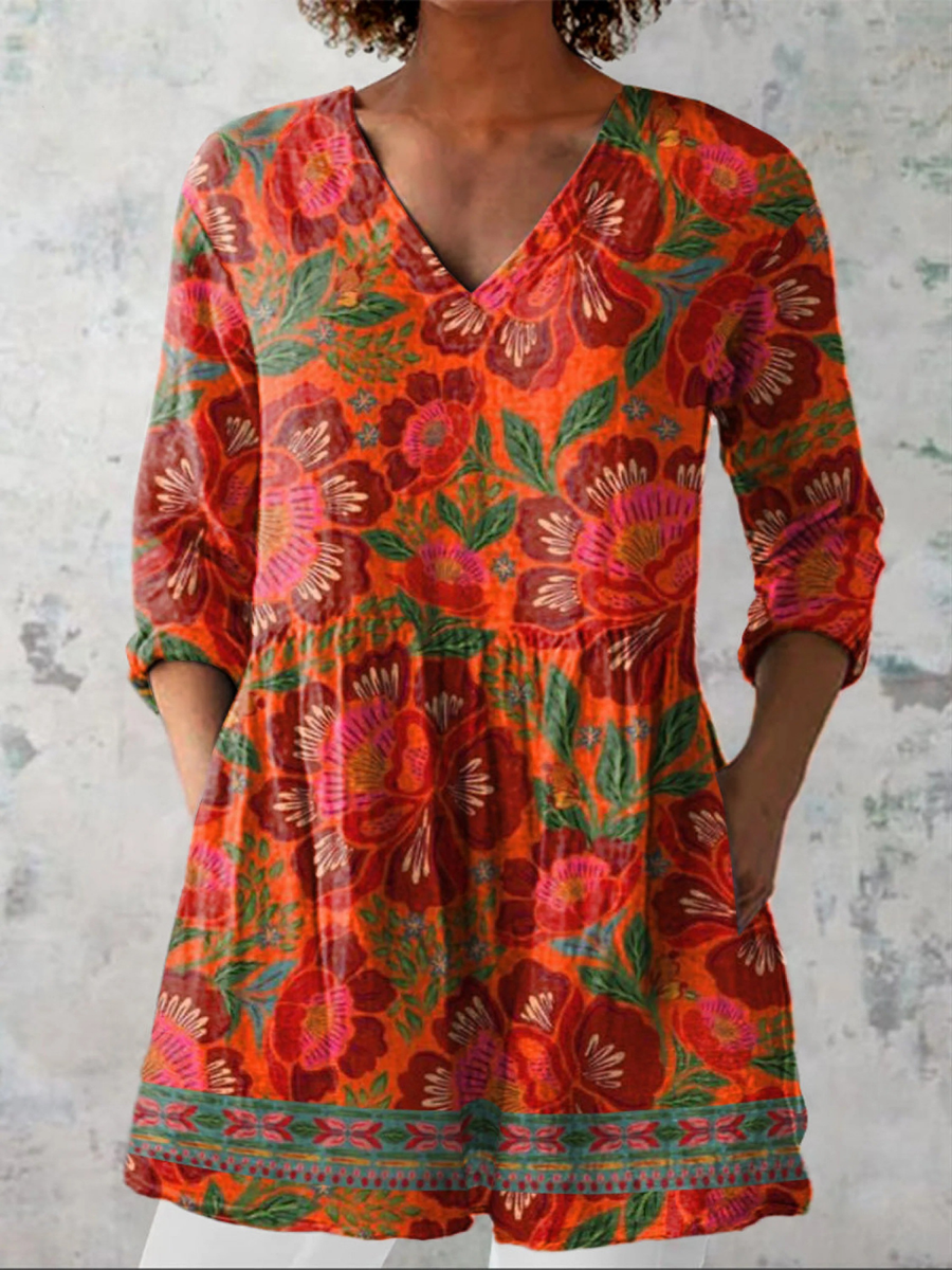 Long-sleeve V-neck blouse in red-orange with colorful floral print and gathered waist