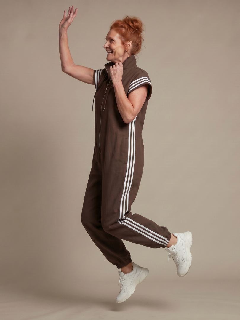 Brown jumpsuit with front zipper, hood drawstrings, and white stripe side panels