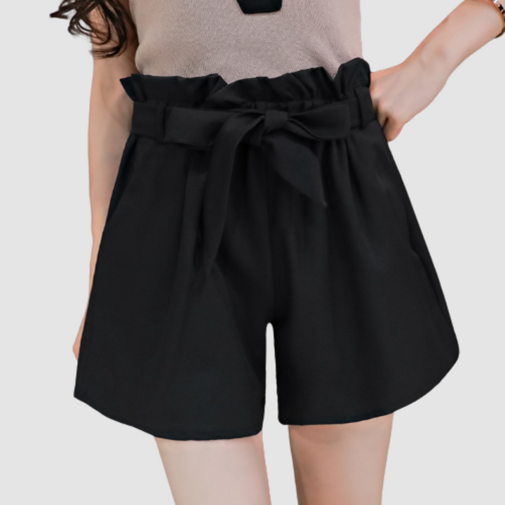 Black paperbag waist shorts with tied bow and pleated front, elastic waistband.