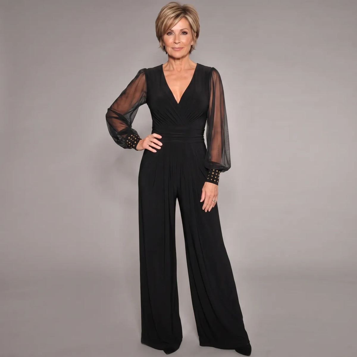 Black evening jumpsuit with V-neck, ruched waist, sheer long sleeves, and wide legs.