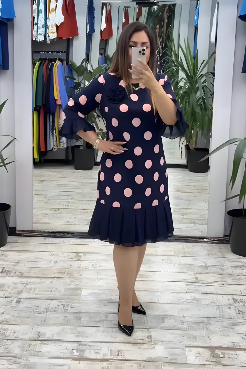 Navy midi dress with pink polka dots, ruffled short sleeves, and pleated skirt