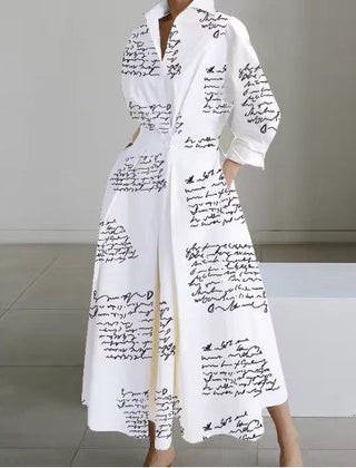 White shirt dress with black script print, long sleeves, and button front