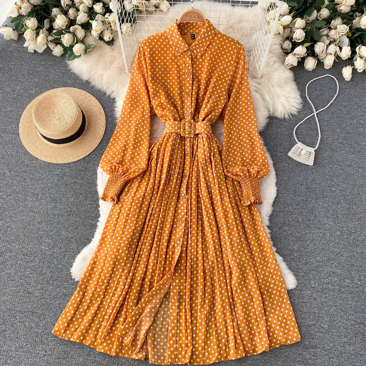 Orange polka dot chiffon pleated dress with button front, long sleeves, tied waist.