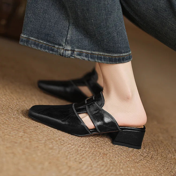 Black leather mule side view with cutout strap, buckle closure, and low block heel