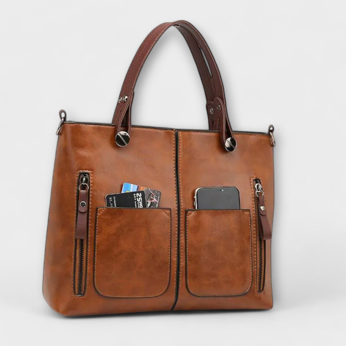 Brown leather tote bag with top handles, multiple front zip pockets, and card slot.