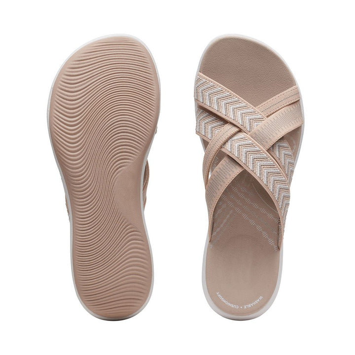 Beige sandals showing textured footbed and chevron strap upper.