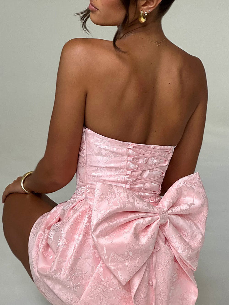 Pink jacquard mini dress showing back view, corset lacing and large waist bow
