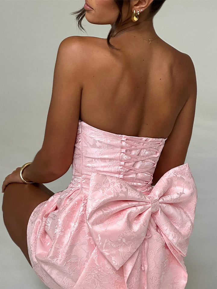 Pink jacquard mini dress showing back view, corset lacing and large waist bow