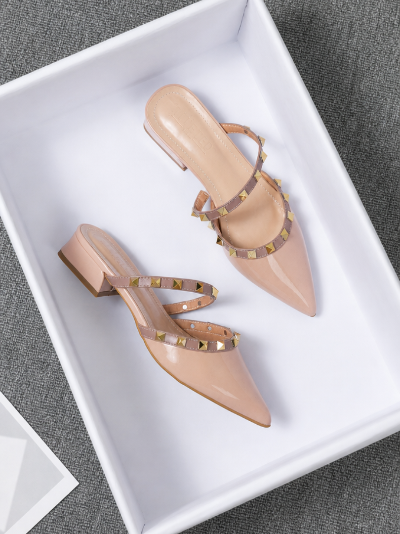 Beige stud-strap mules with pointed toe and low block heel, side buckle detail