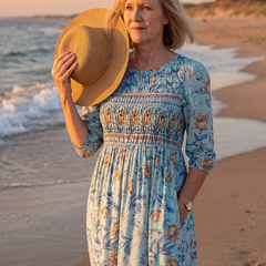 Sky blue floral midi dress with gathered waist, three-quarter sleeves; straw hat in hand