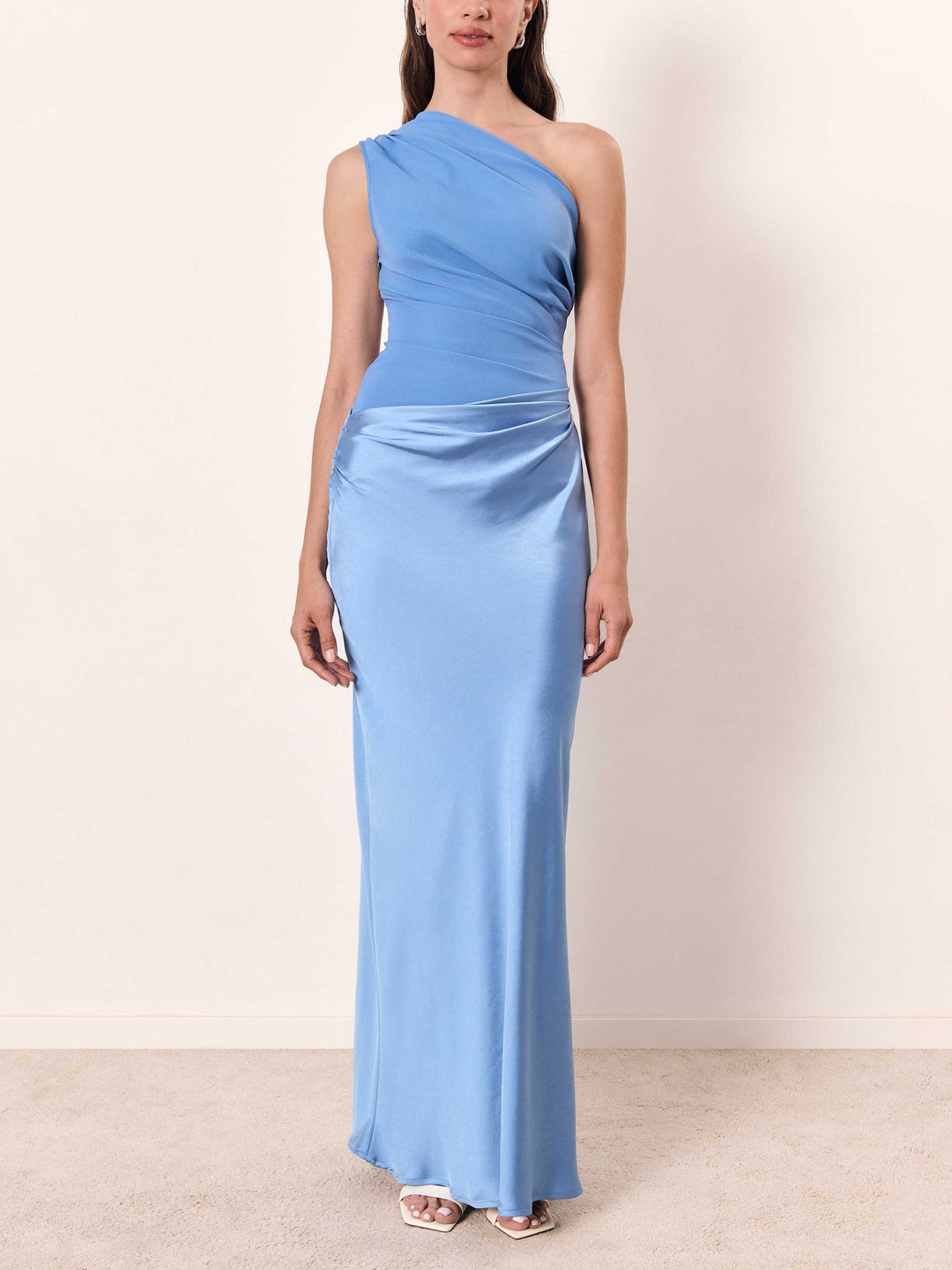 One-shoulder satin maxi dress in light blue with pleated waist and long straight silhouette.