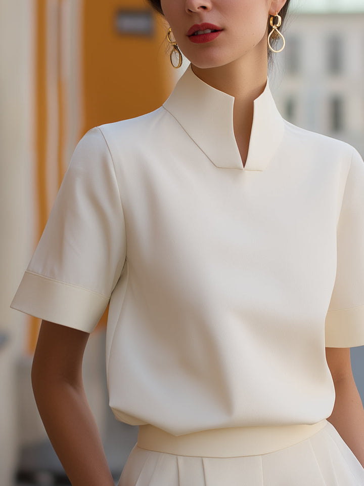 White structured blouse with stand collar and short sleeves, neat minimalist neckline