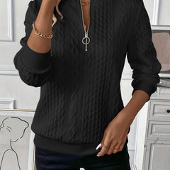 Black zip-up cable knit sweater with long sleeves and metal zipper pull at center front