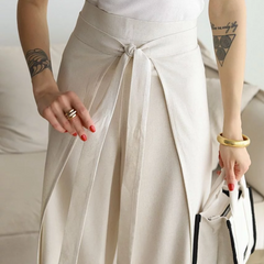 Light cream wide-leg trousers close-up, knotted front tie cinching the waist