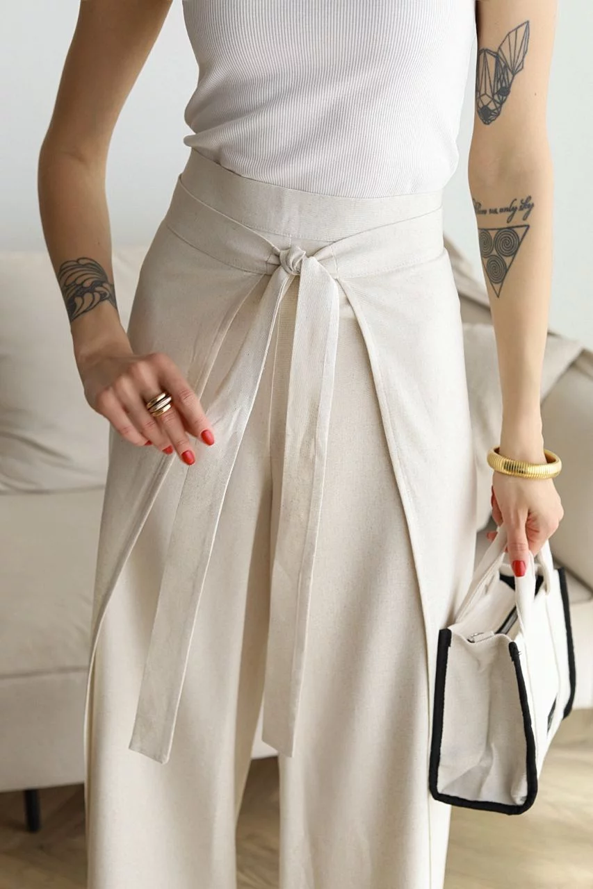 Light cream wide-leg trousers close-up, knotted front tie cinching the waist