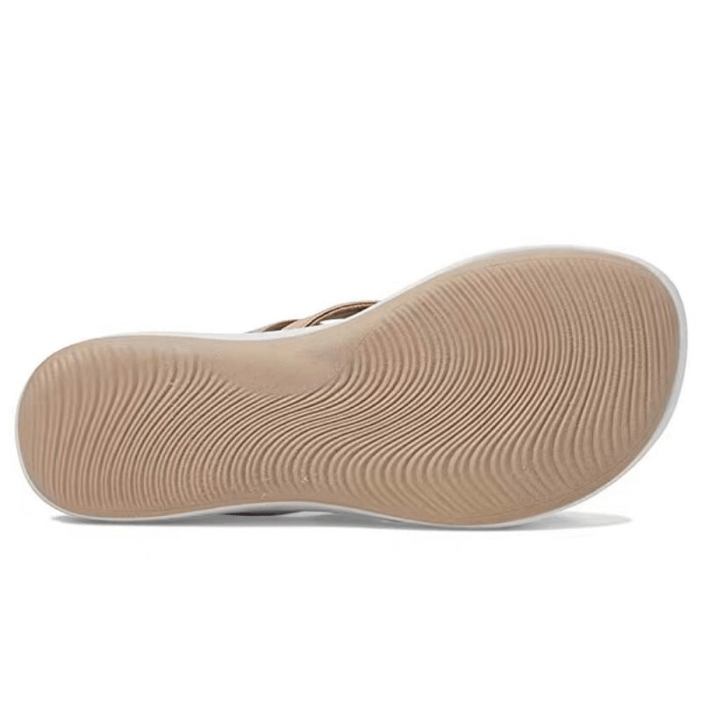 Beige sandal outsole with wavy textured tread underfoot.