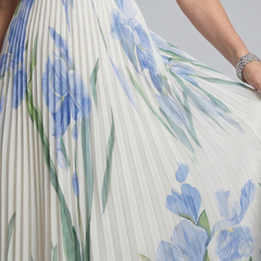 White midi dress with blue floral print, green accents, pleated skirt detail