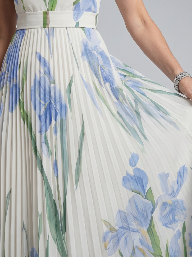 White midi dress with blue floral print, green accents, pleated skirt detail