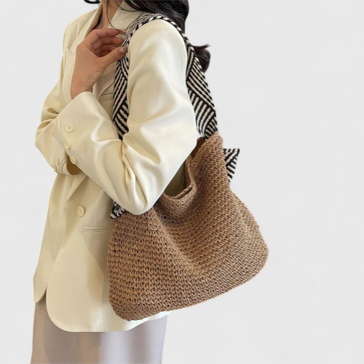 Woven warm-brown boho tote bag with striped handle ties, shown in side profile