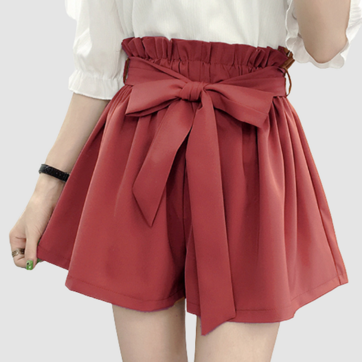 Red paperbag waist shorts with tied bow and pleated elastic waistband.